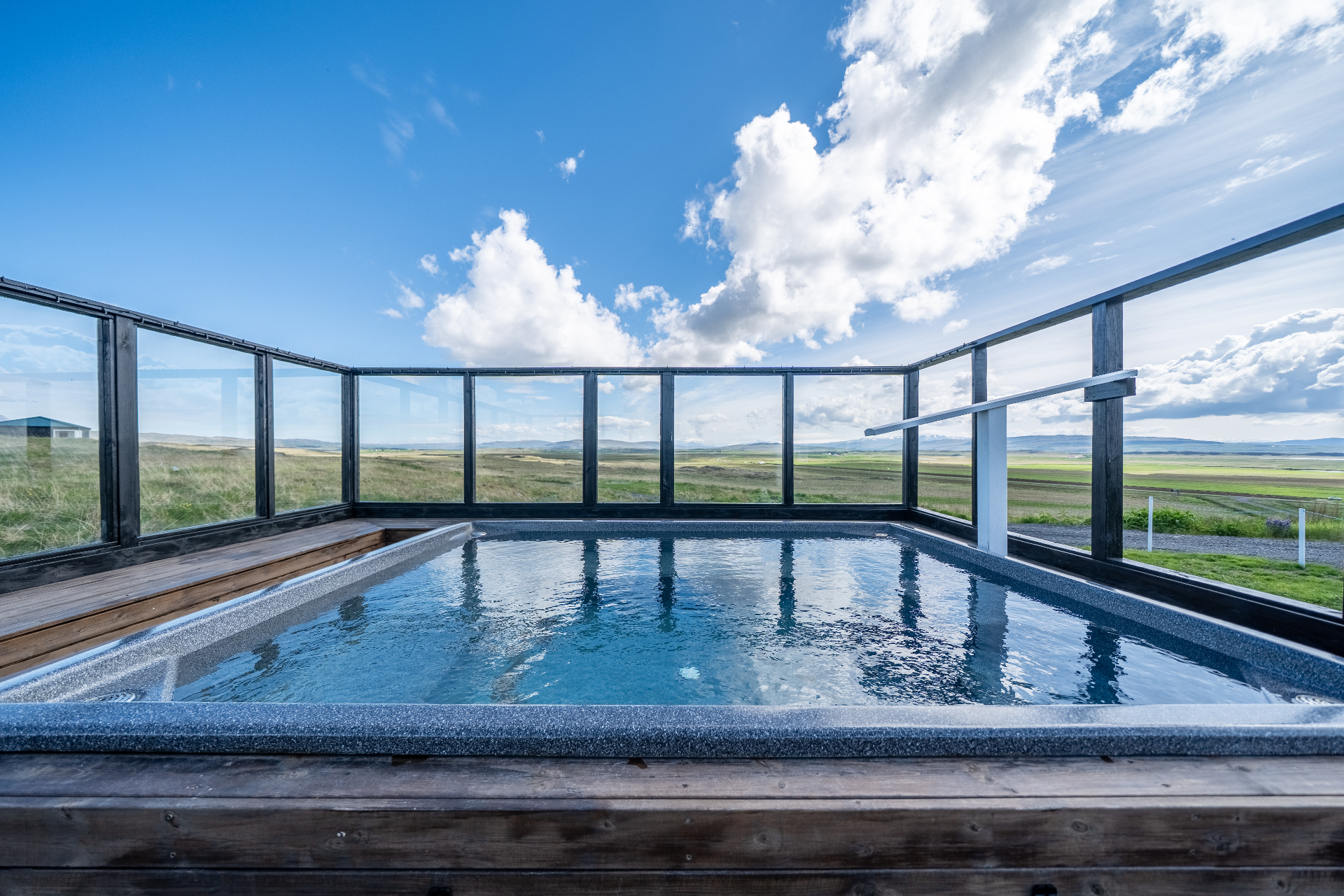 Outdoor hot tub on a wooden deck with sweeping views over the Borgarfjörður countryside