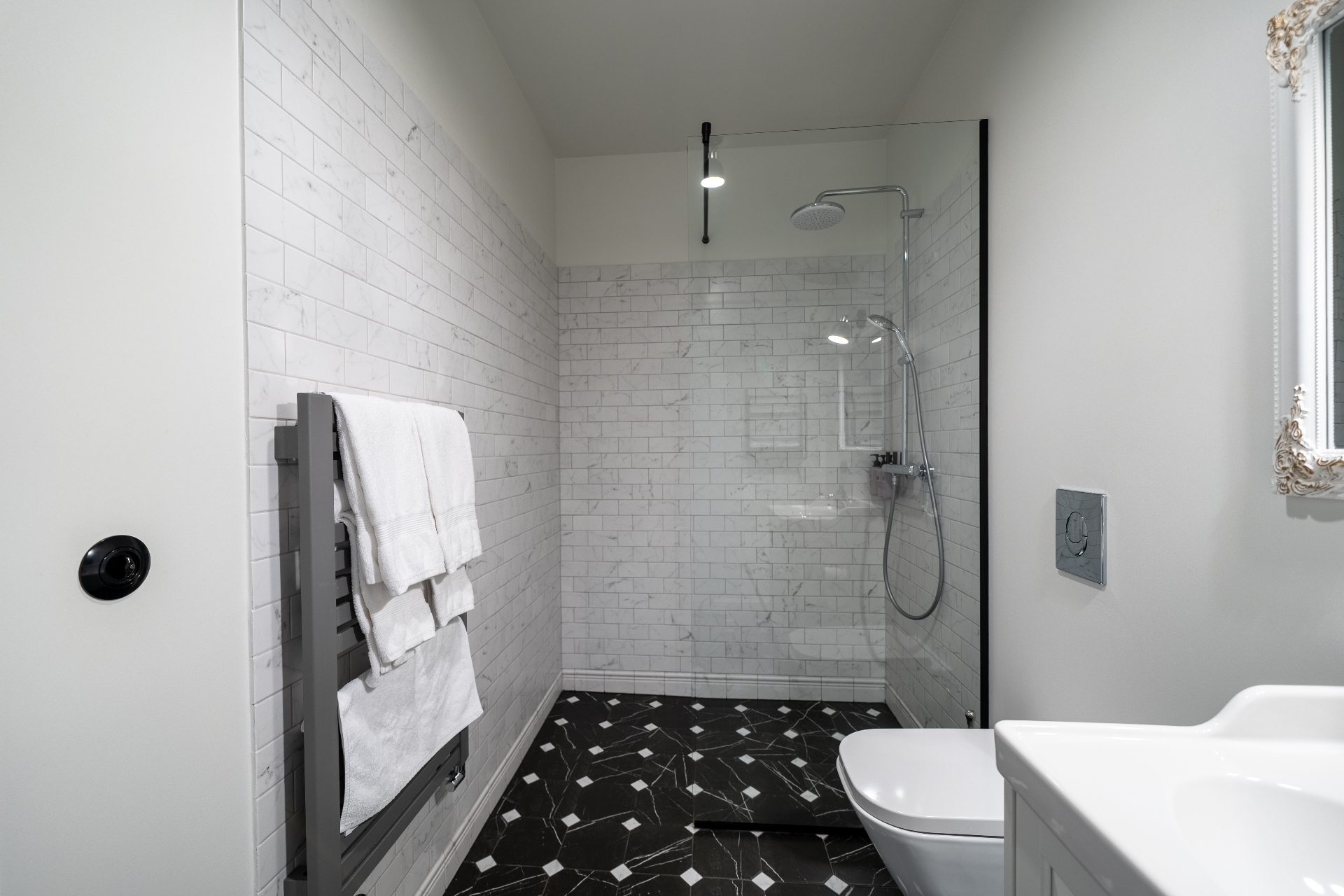 Private bathroom with walk-in marble-tiled shower and vintage mirror