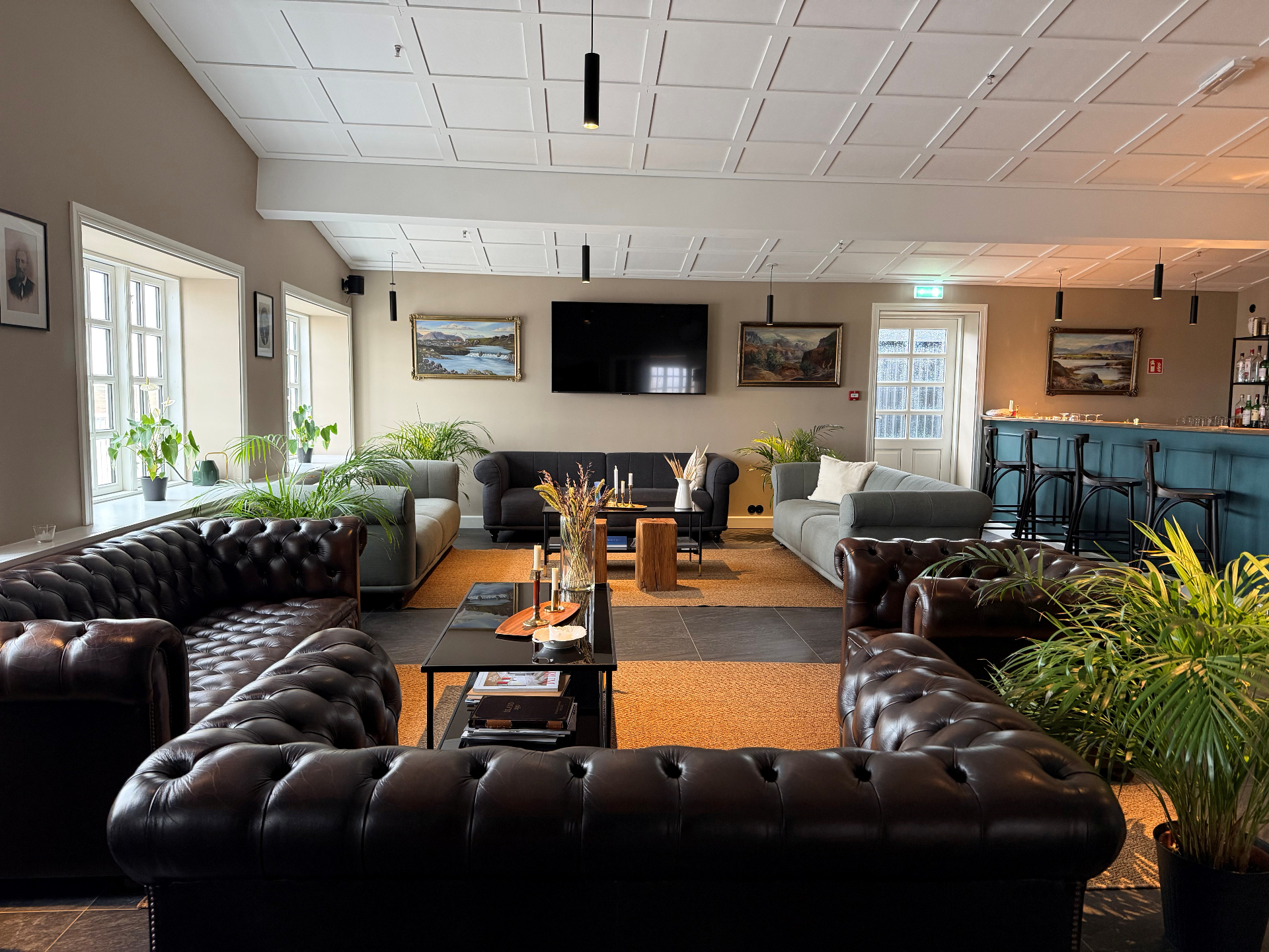 Lounge with Chesterfield leather sofas, plants and a teal bar