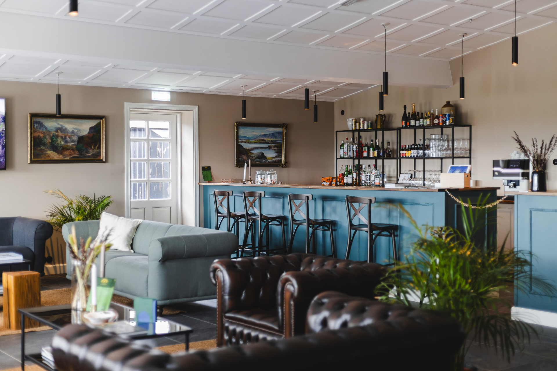 Teal bar with wooden top and shelves of spirits and glassware